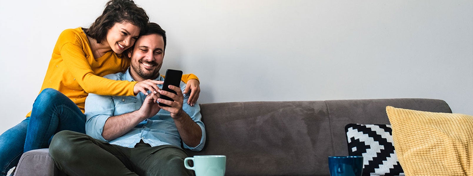 couple on couch paying bill on mobile devices